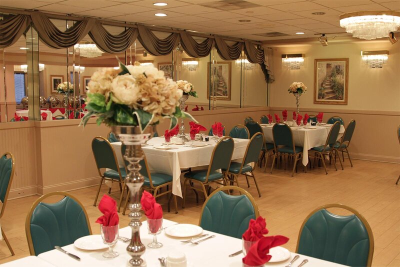 Party room with tables decorated with flower vases and red linen