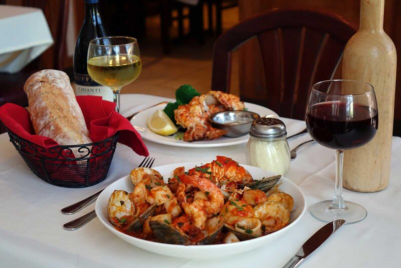 Zuppa de pesce with a basket of bread and a glass of white and red wine