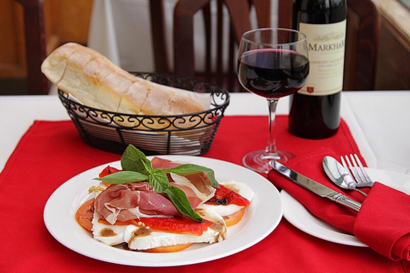 Caprese salad with a basket of bread and a glass of red wine